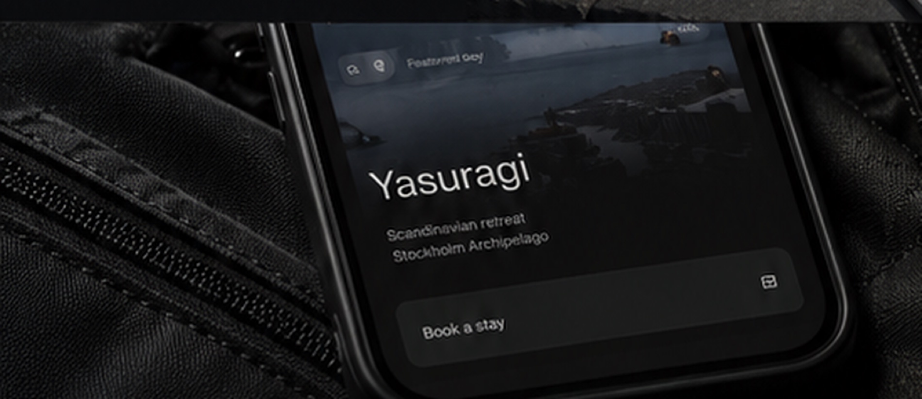A phone resting on a dark bag, showing a retreat listing with a Book a stay button.
